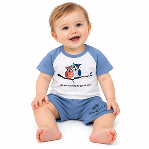 Baby modelling the blue and white owl T-shirt and shorts set on a pure white background