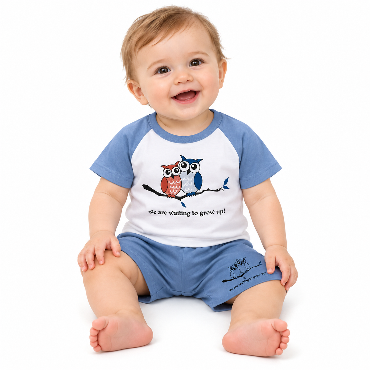 Baby modelling the blue and white owl T-shirt and shorts set on a pure white background