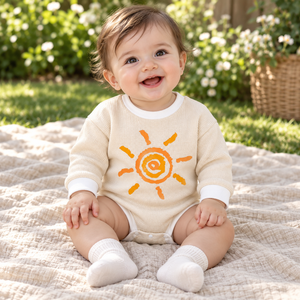 Baby styling the beige sun print romper outdoors on a spring day